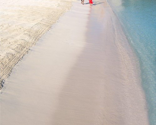 A couple walking along a white sand beach