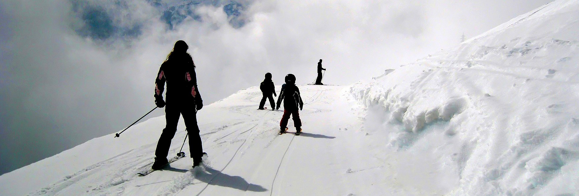 Parent skiing behind children on white snowy piste