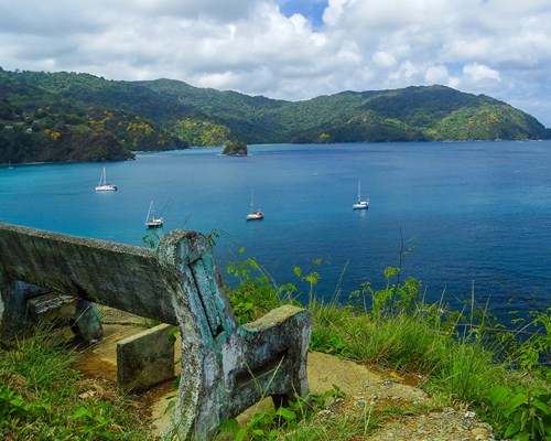 A old bench on top a hill overlooking several yachts in a bay