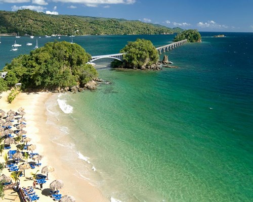 Sun beds and beach umbrellas lined up on a narrow tropical beach
