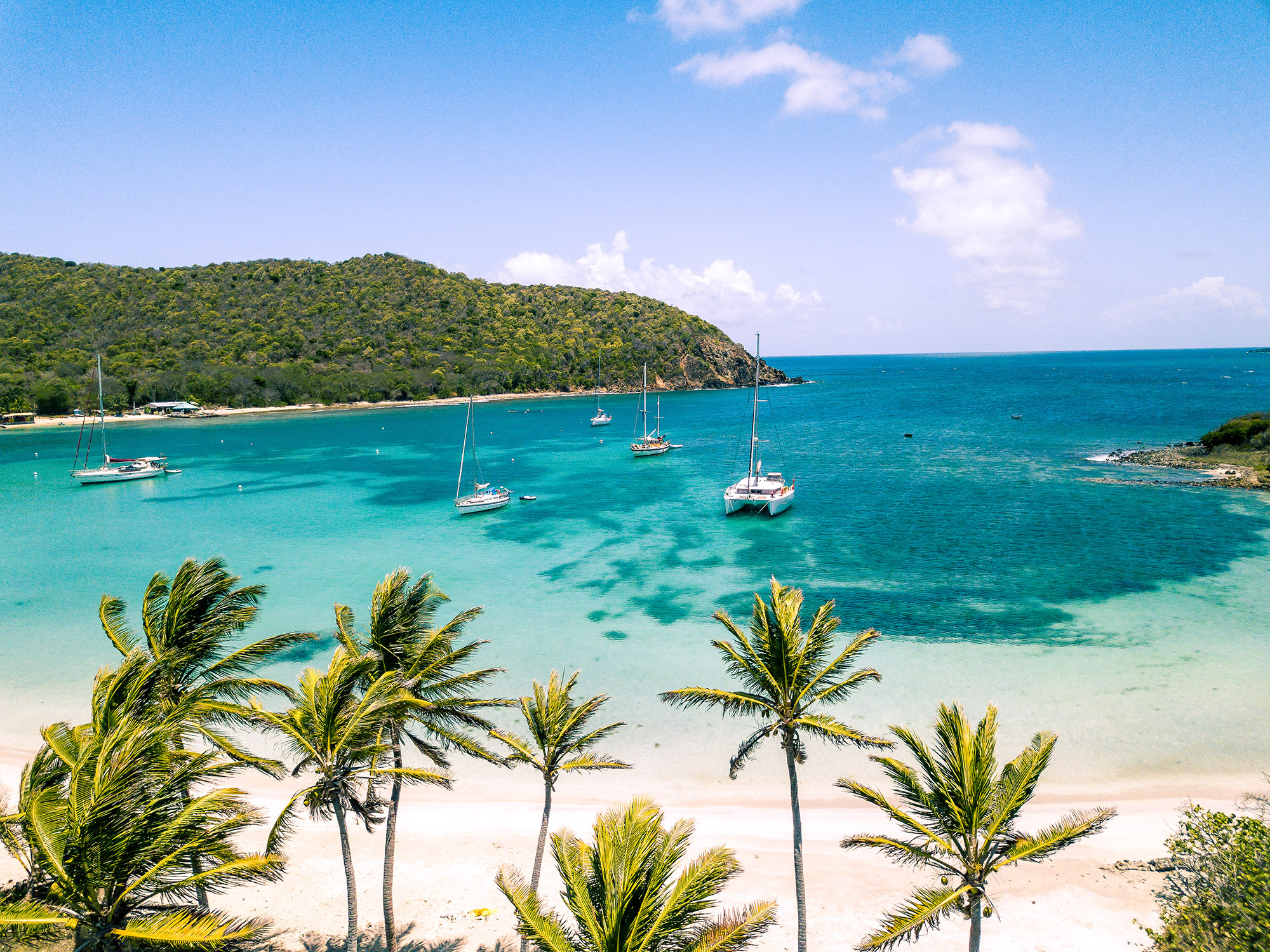 Aerial view of white sand Caribbean beach with sailing boats docked in the bay