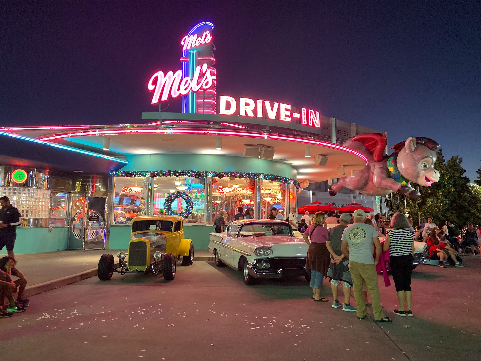 People standing with classic cars at Mels Drive-in