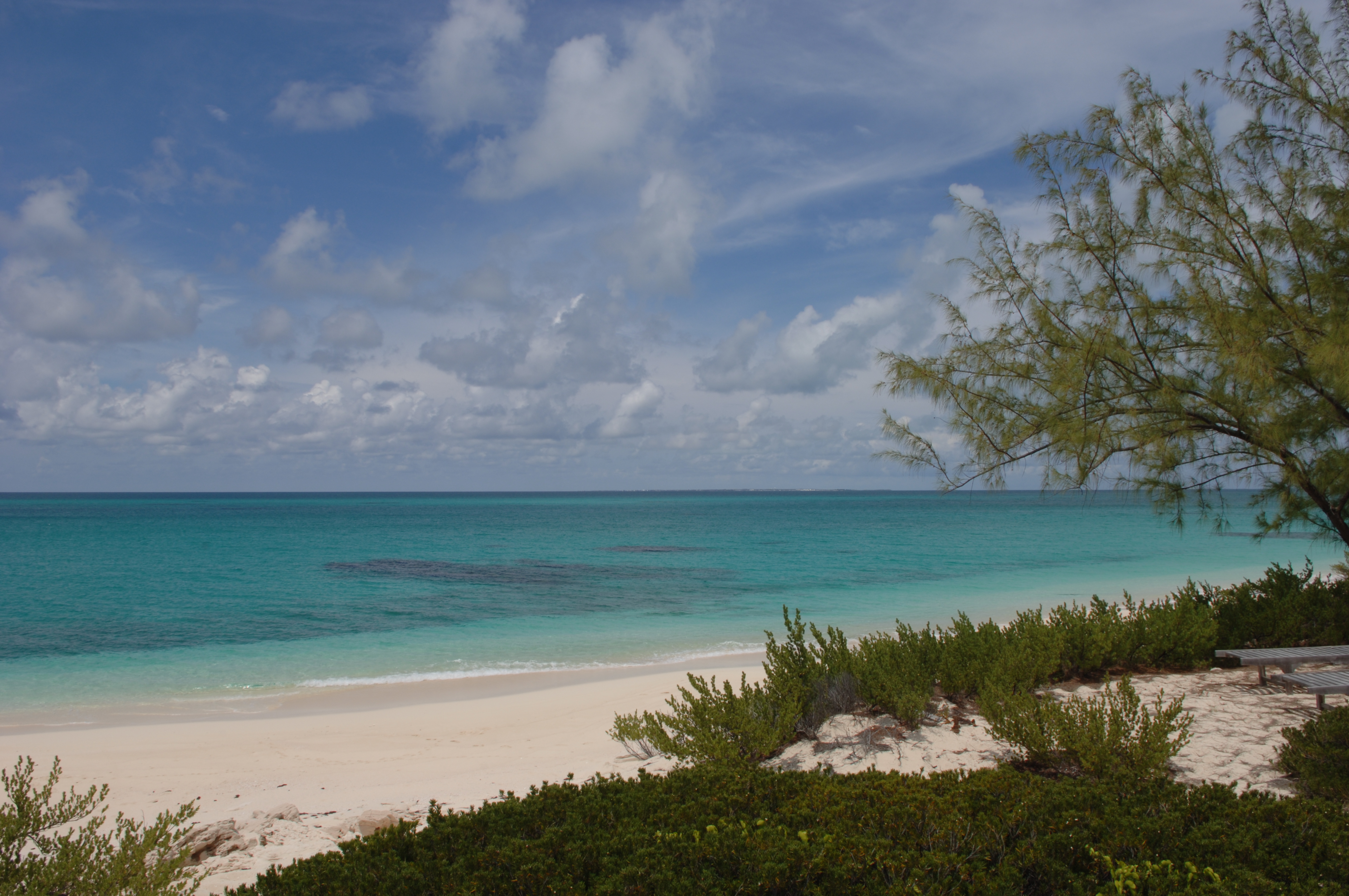 Tropical stretch of beach with white sand and shallow reefs in a turquoise sea