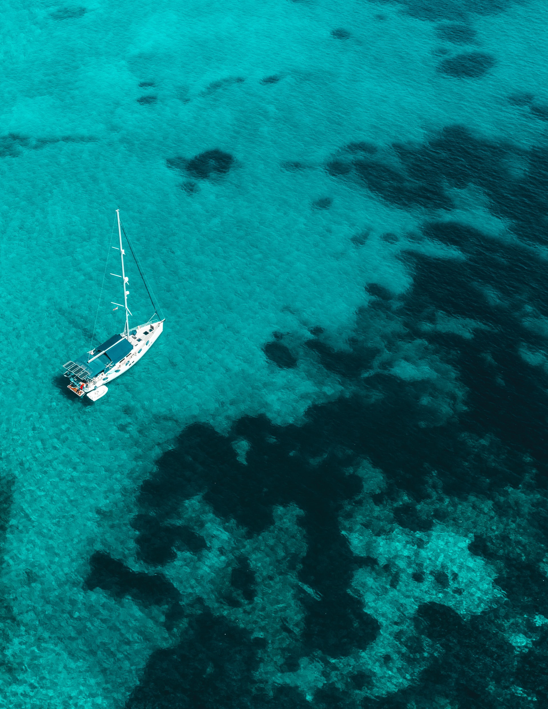 Sailing boat docked in clear turquoise tropical sea 