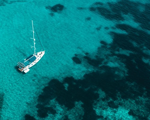 Sailing boat docked in clear turquoise tropical sea
