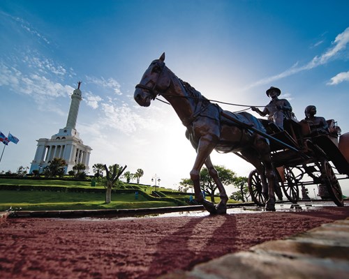 A statue of a horse drawn carriage next to an important white building