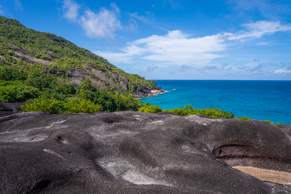 Rocky walking trail looking out to blue oceans and green hills