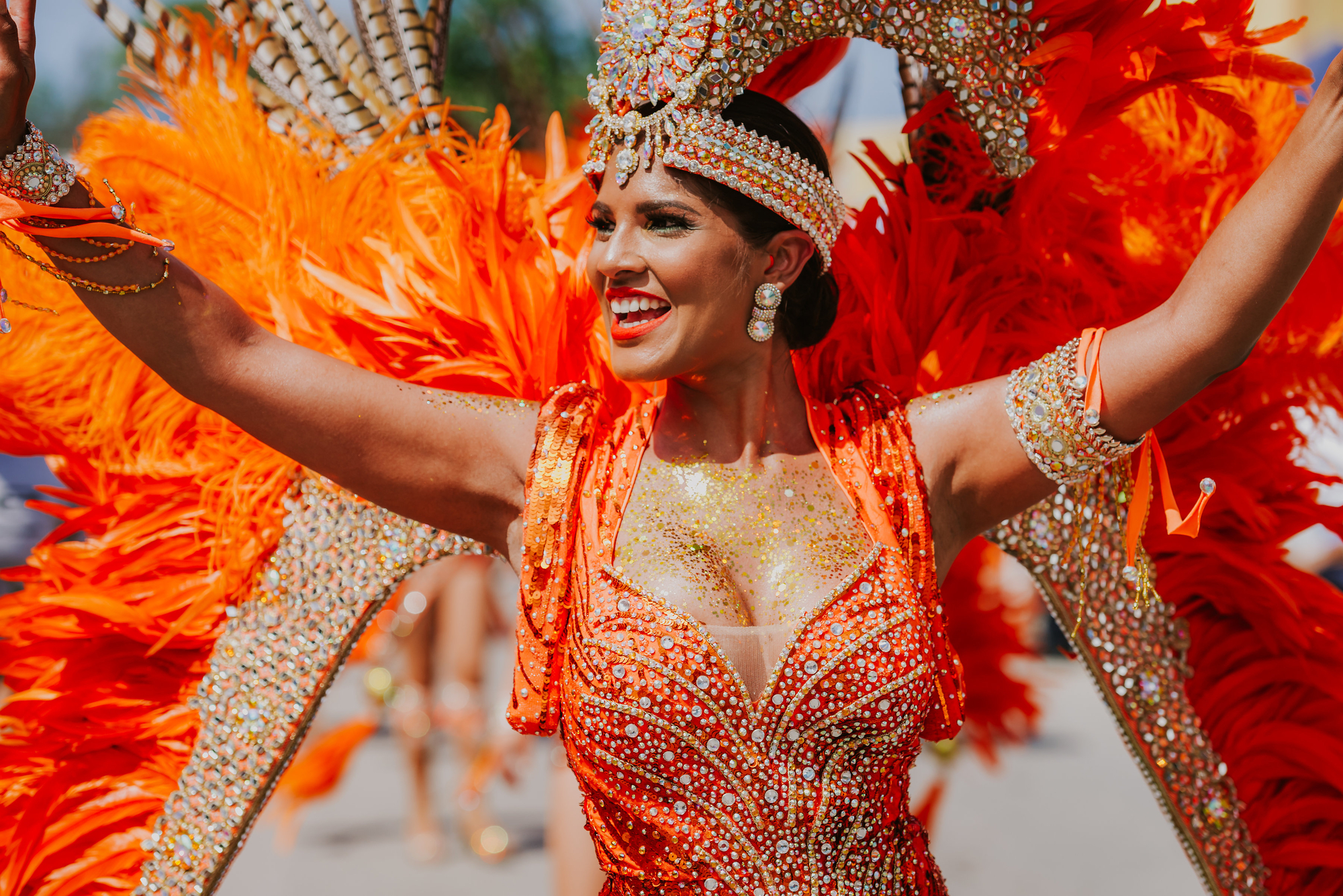 Woman in bright orange costume at a carnival on a sunny day