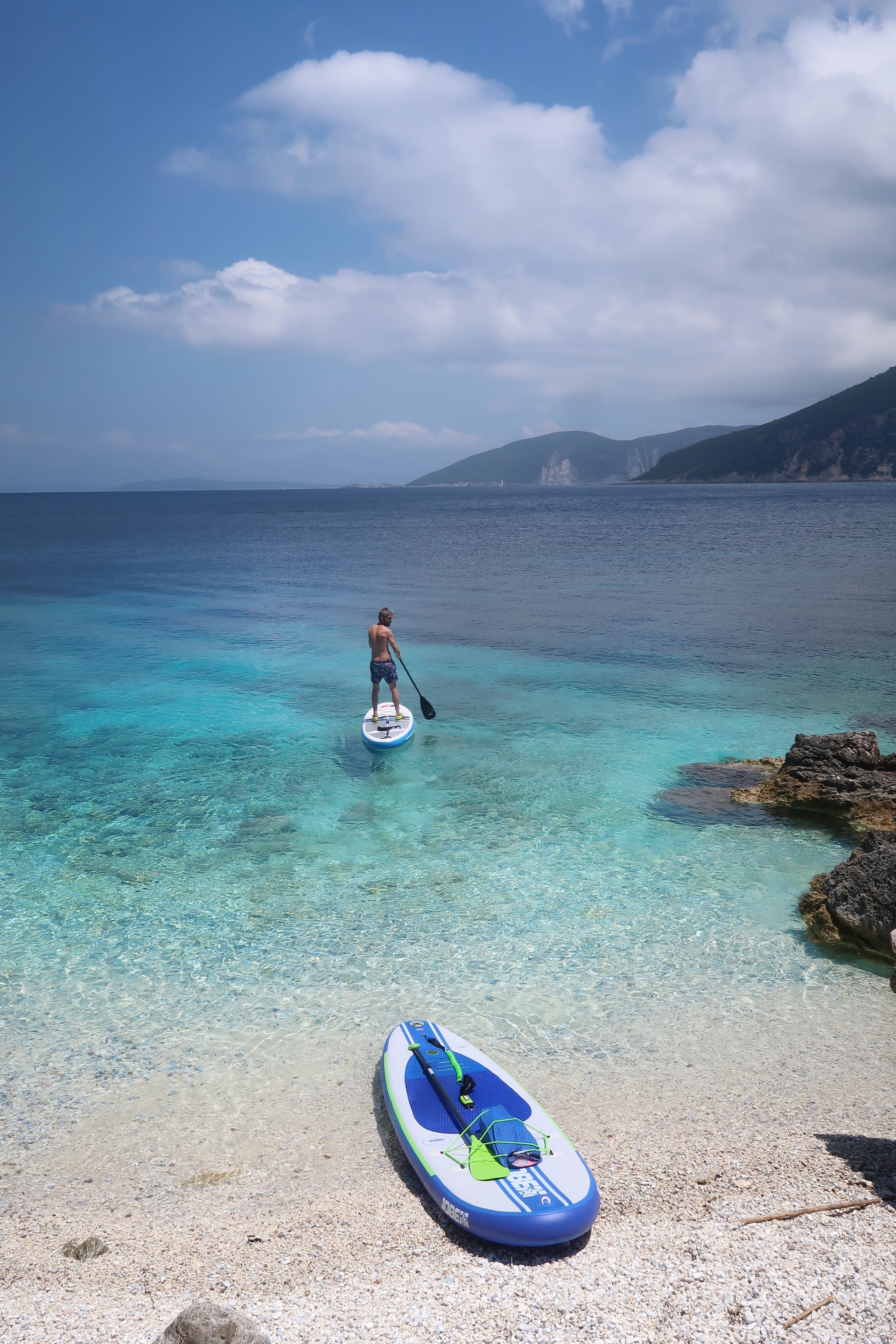 A person kayaking on the crystalline ocean near the shore