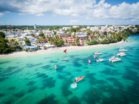 Aerial view of several small boats docked near a tropical white sand beach and town