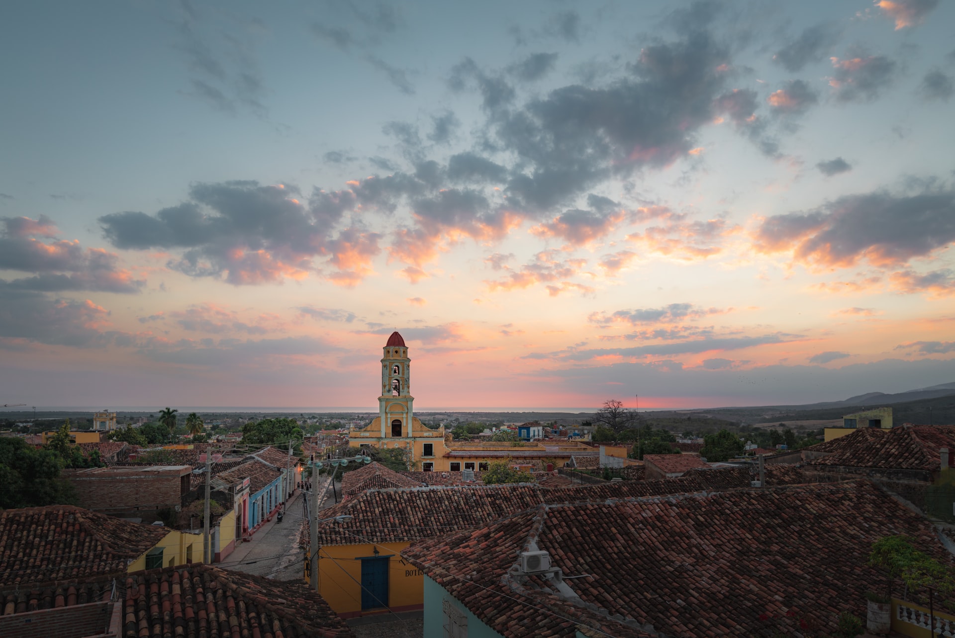 Aerial view of an old city full of charming colourful buildings with terracotta tiled roofs with a pink sunset sky