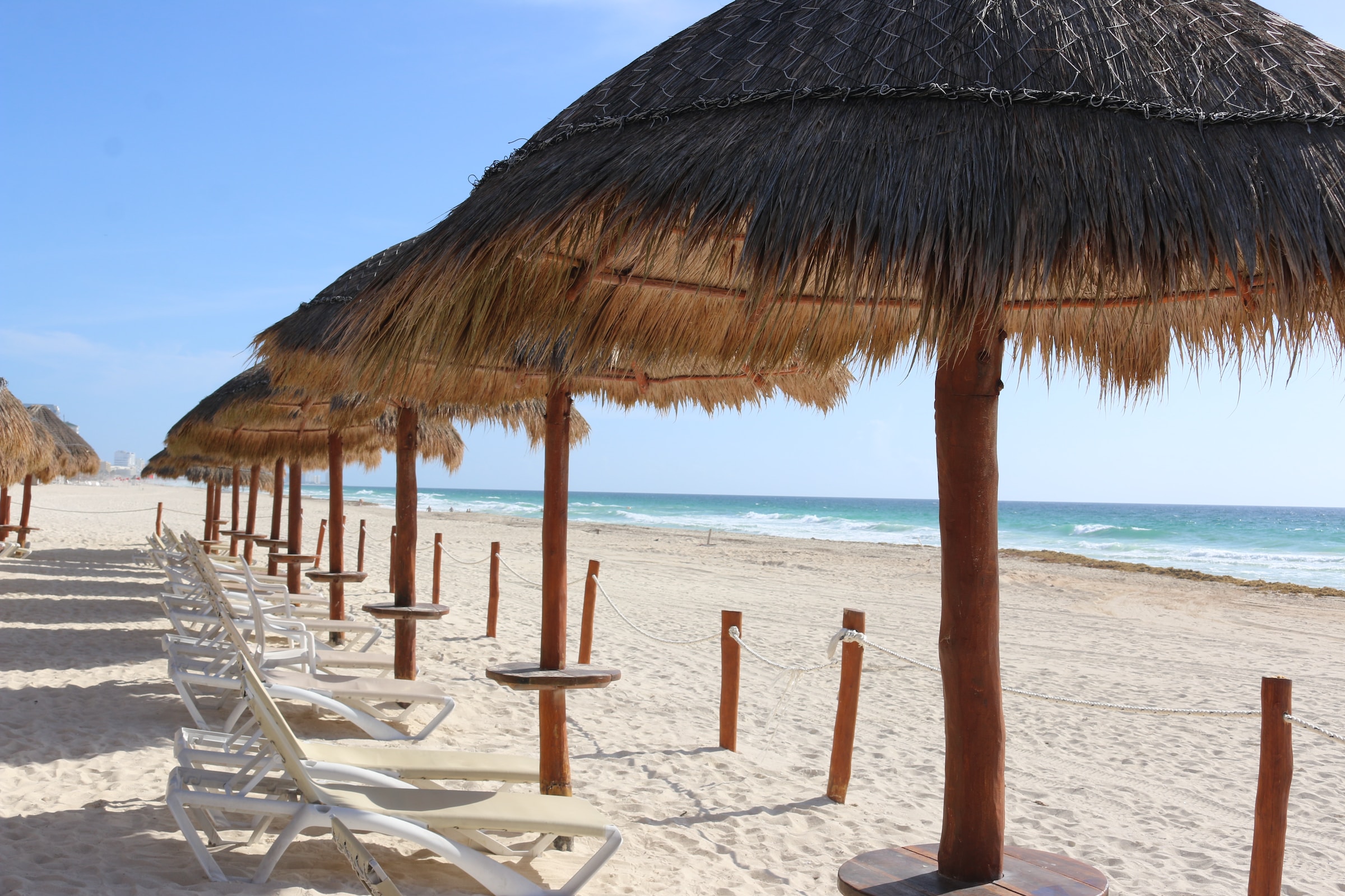 Rows of thatched parasols at a light-sanded beach