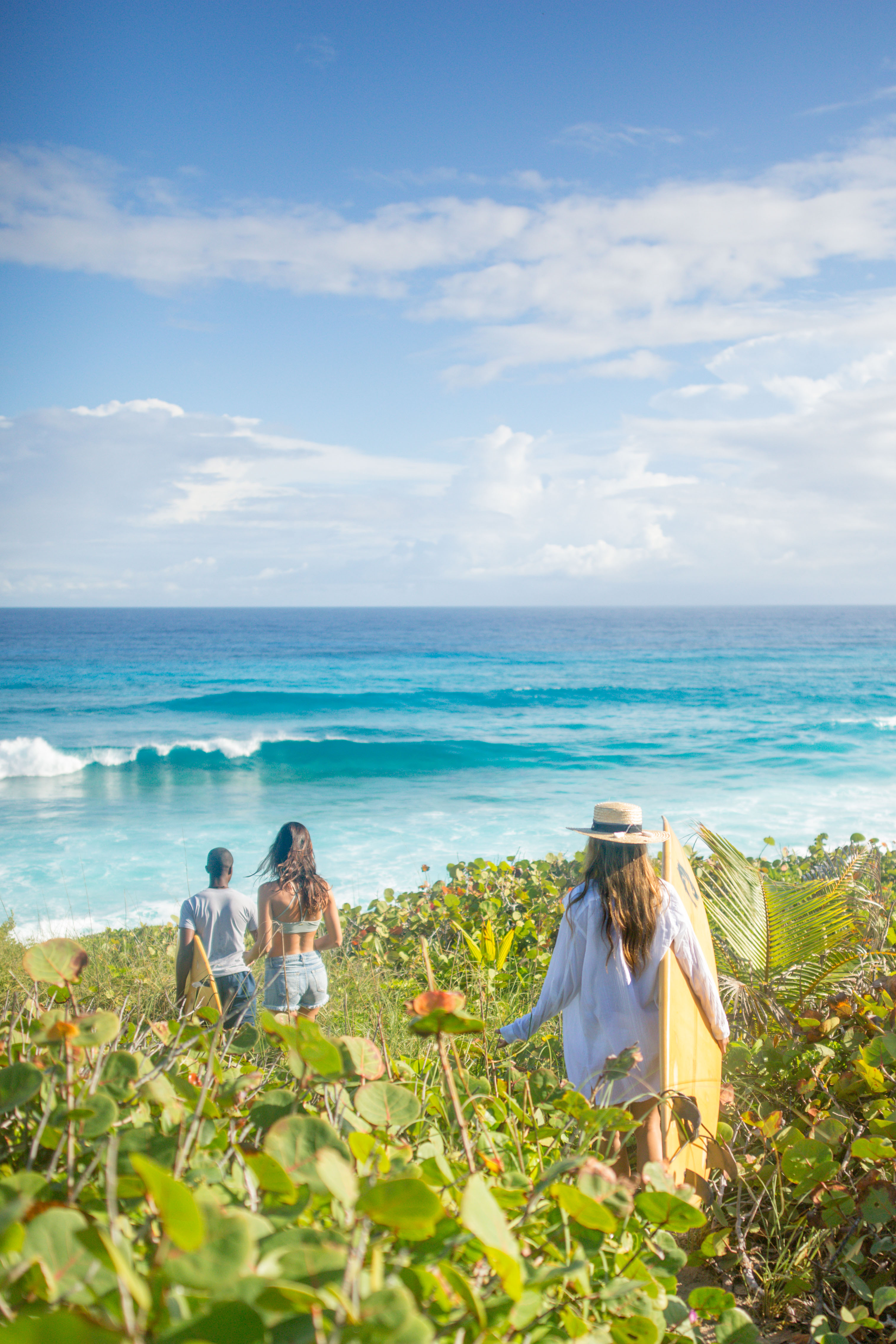 Friends with surfboards walking to Surfers Beach in Eleuthera