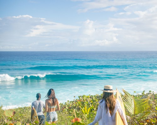 Friends with surfboards walking to Surfers Beach in Eleuthera