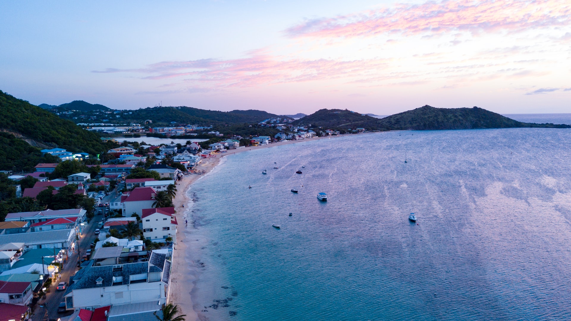 Aerial view of a coastline of a town on a tropical island with purple sunset sky