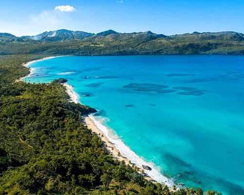 Aerial view of a tropical beach and surrounding forests and mountains