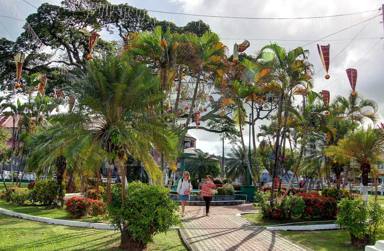 2 women walking past a large green water fountain in Castries town centre