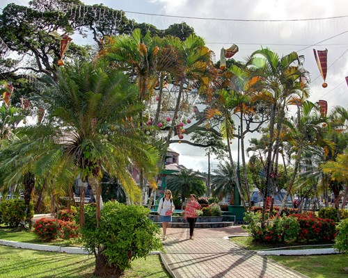 2 women walking past a large green water fountain in Castries town centre