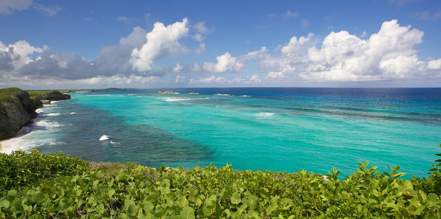 Looking down the coast at waves crashing against a headland on a tropical island 