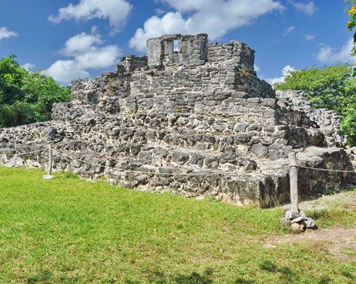 Ruins of an old building surrounded by a lawn and trees -