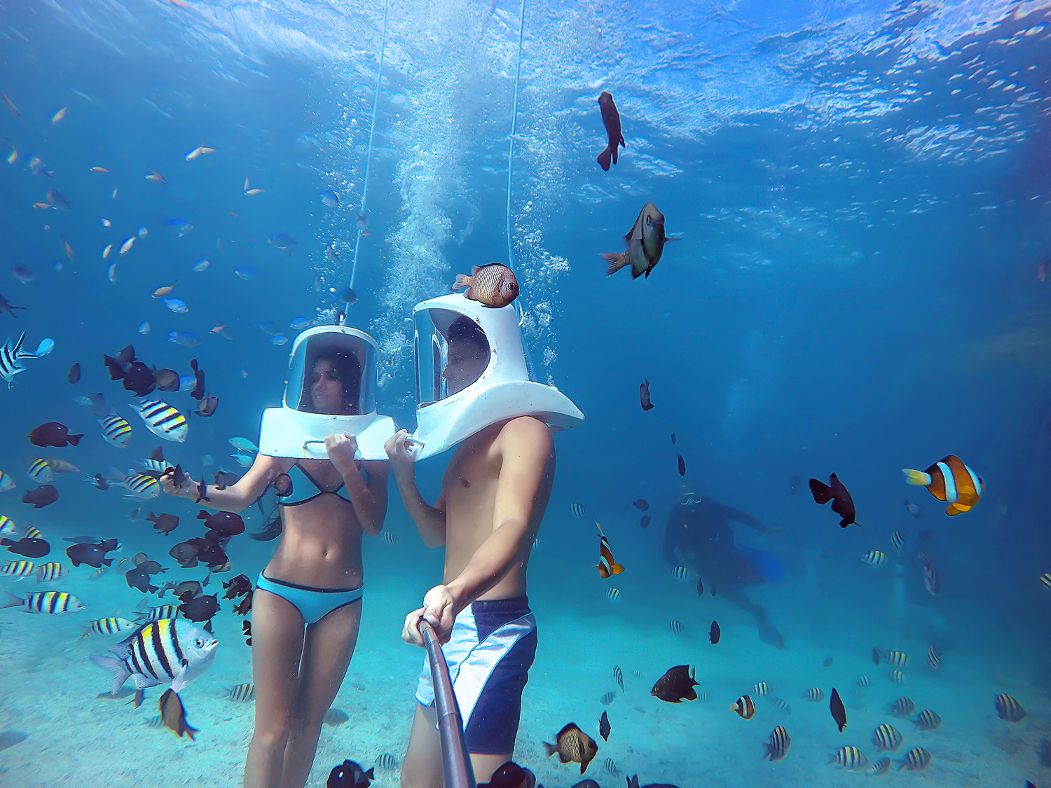 Couple Helmet Diving In Clear Blue Carribean Sea With Tropical Fish