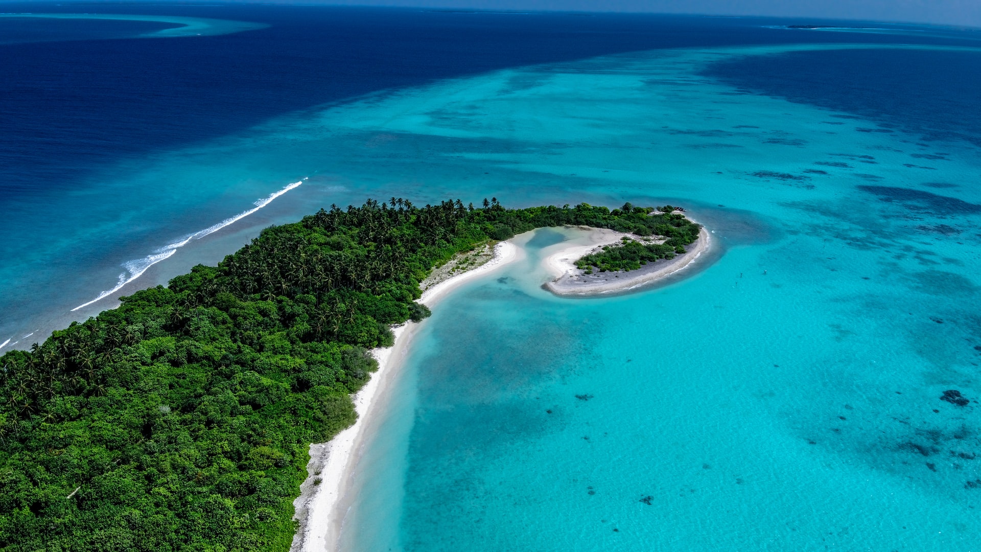 Shoe shaped island stretching across azure ocean with a spiral-like sandbank