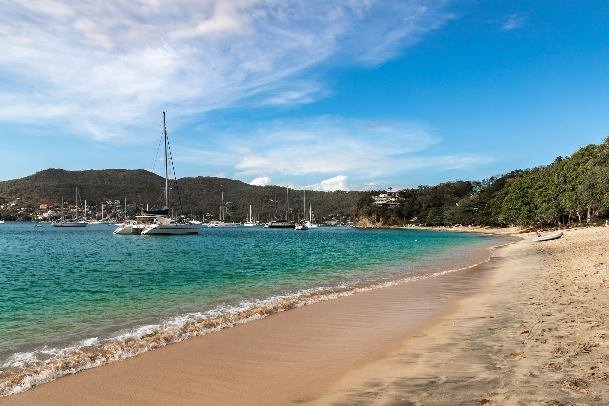 Sailing boats docked in a tropical bay with turquoise sea and golden sand beach
