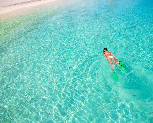 Girl snorkelling in a clear, turquoise tropical sea