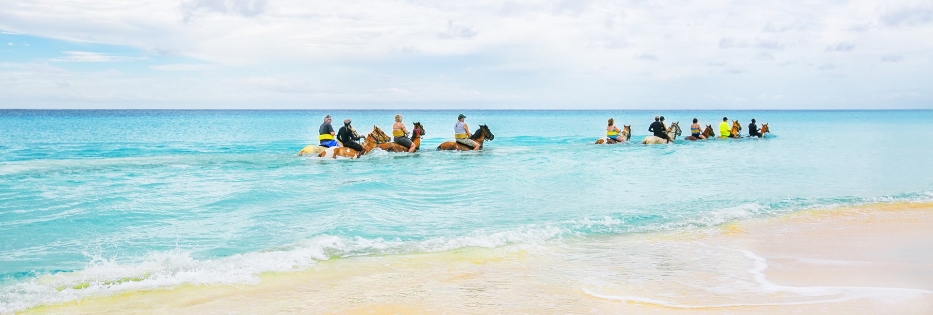 Group of tourists riding horses through the sea