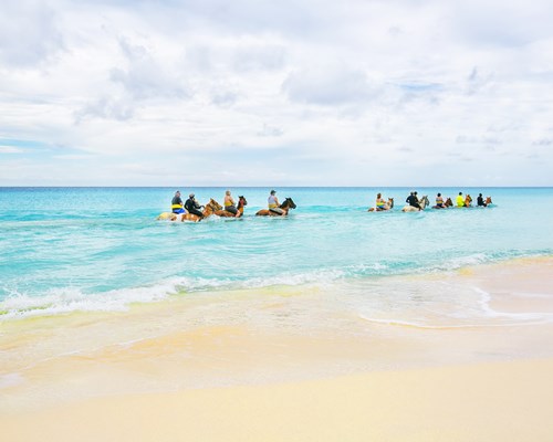 Group of tourists riding horses through the sea
