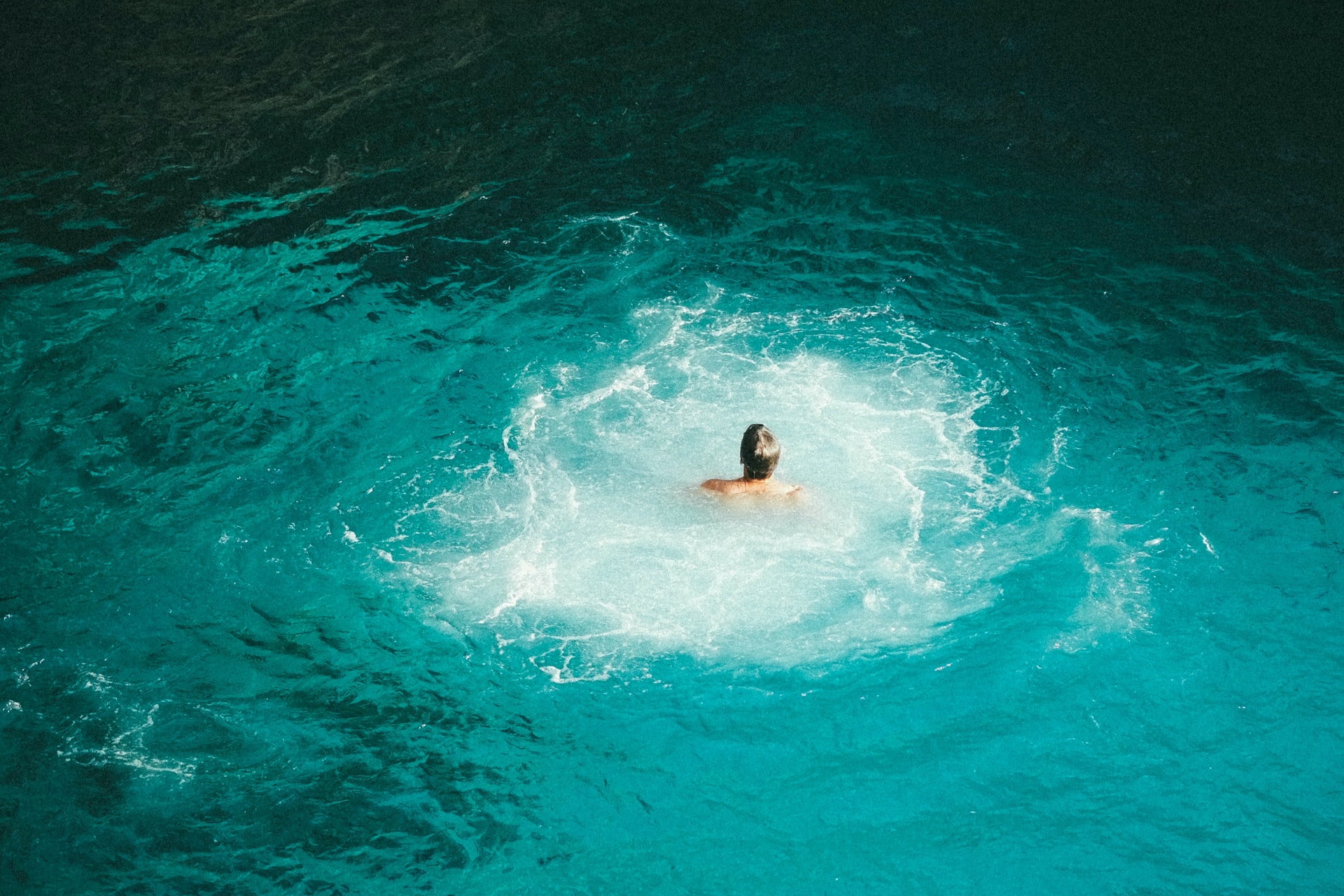 Man swimming in bright blue pool of water