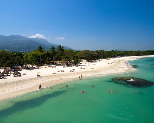 Stretch of tropical beach with people playing in the sea