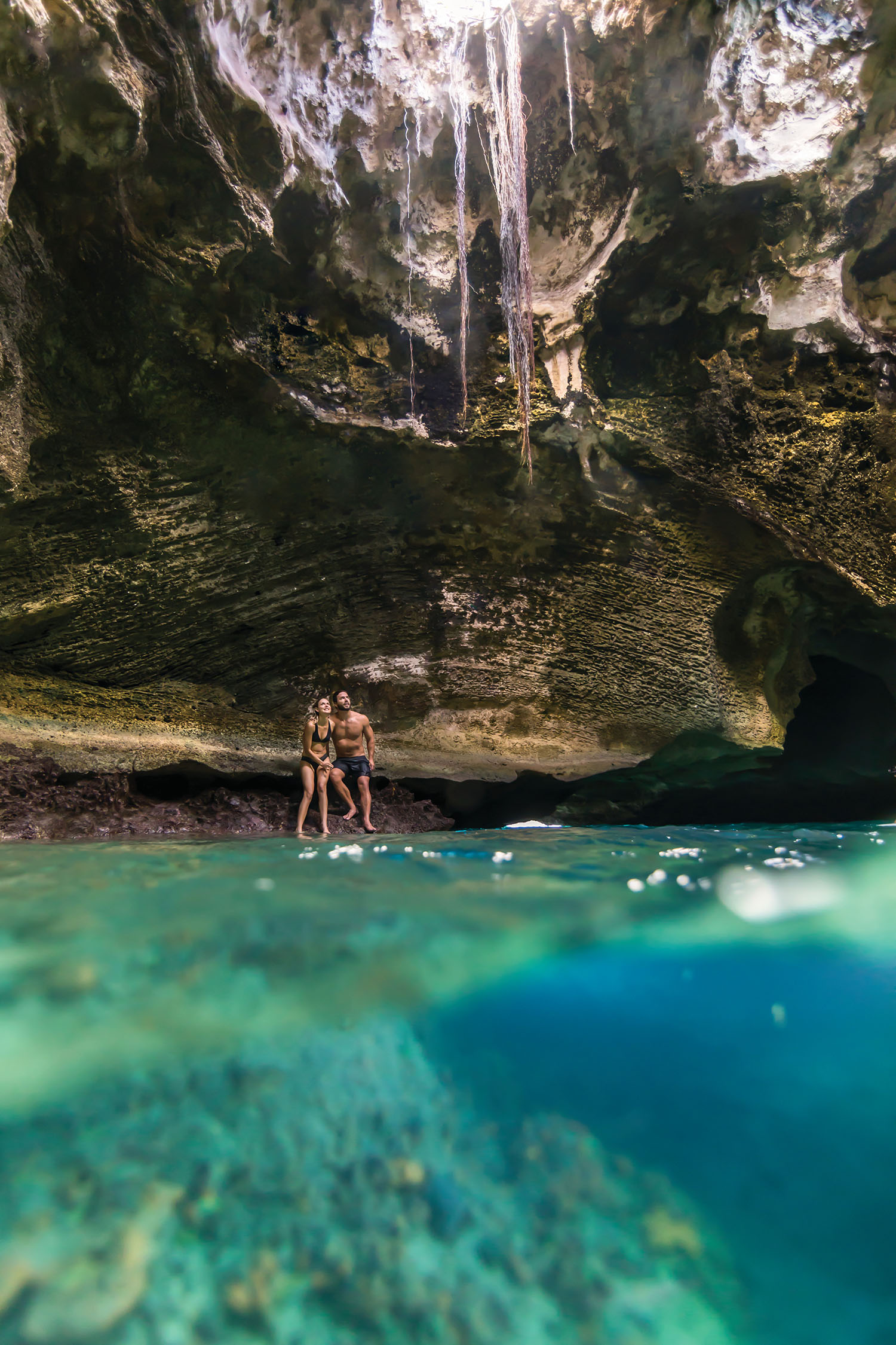 A couple sitting inside Thunderball Grotto cave in Exuma