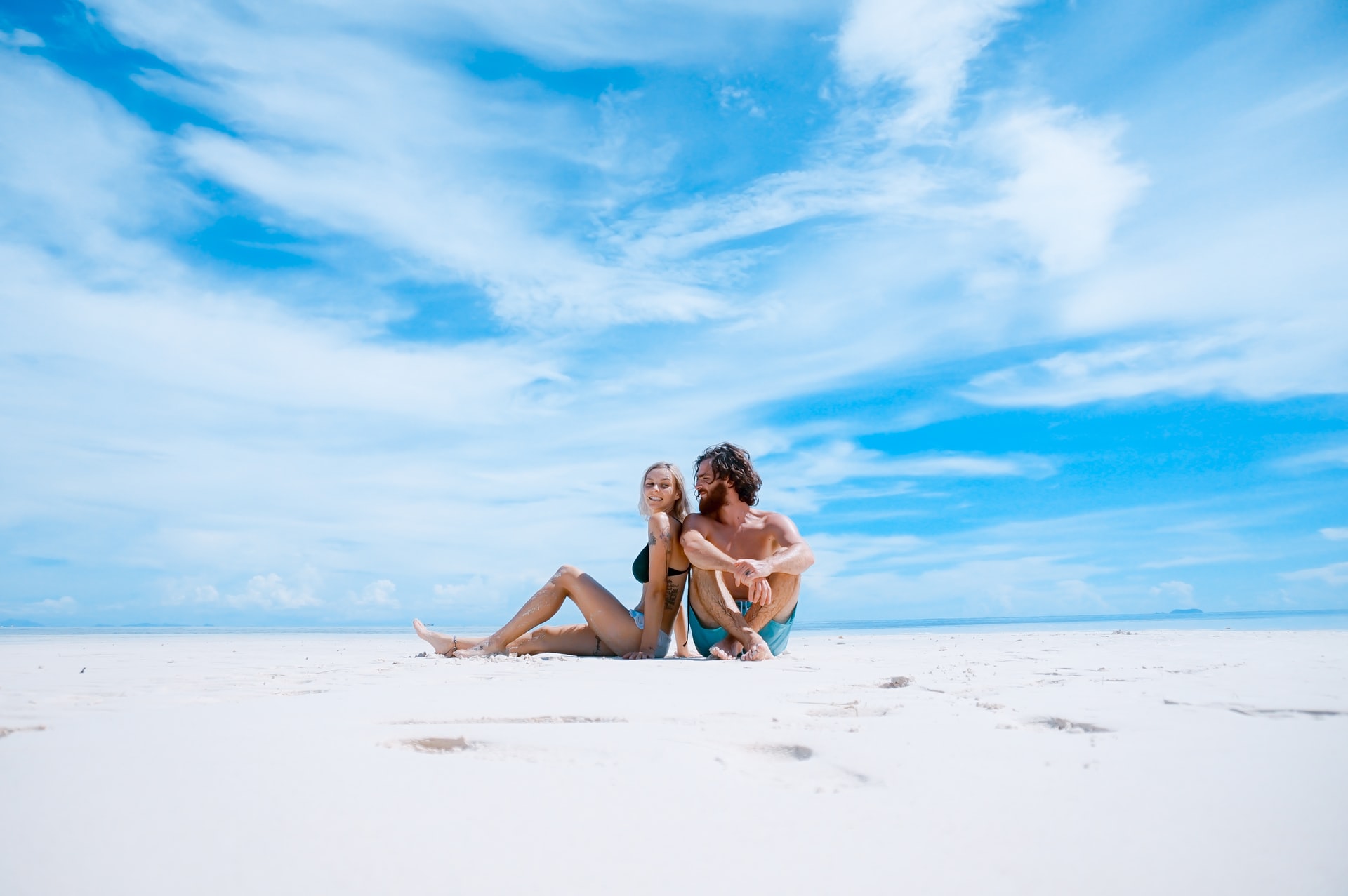 Young couple sitting on an empty white beach