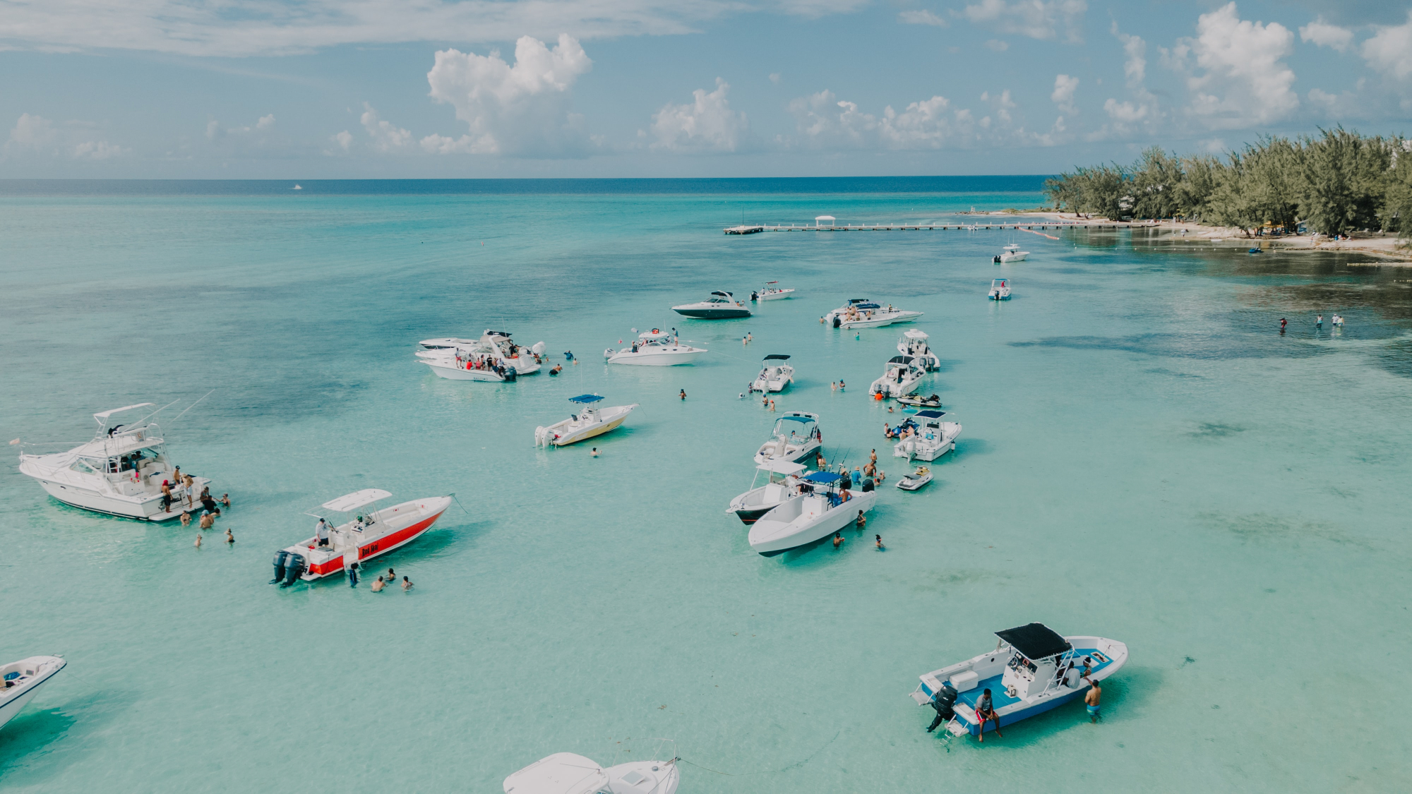 Boats anchored in blue waters with island in background - Cayman Islands 