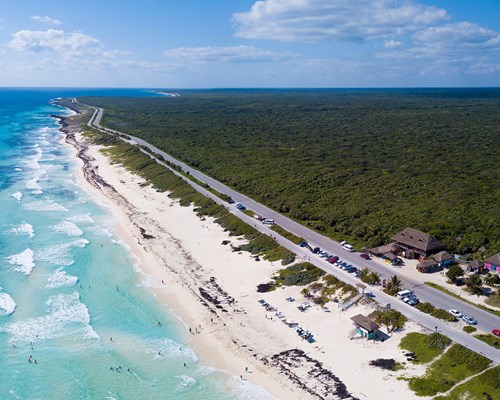 Aerial view of a long stretch of white sand beach with small turquoise waves crashing on the beach