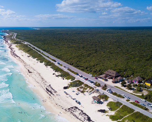 Aerial view of a long stretch of white sand beach with small turquoise waves crashing on the beach