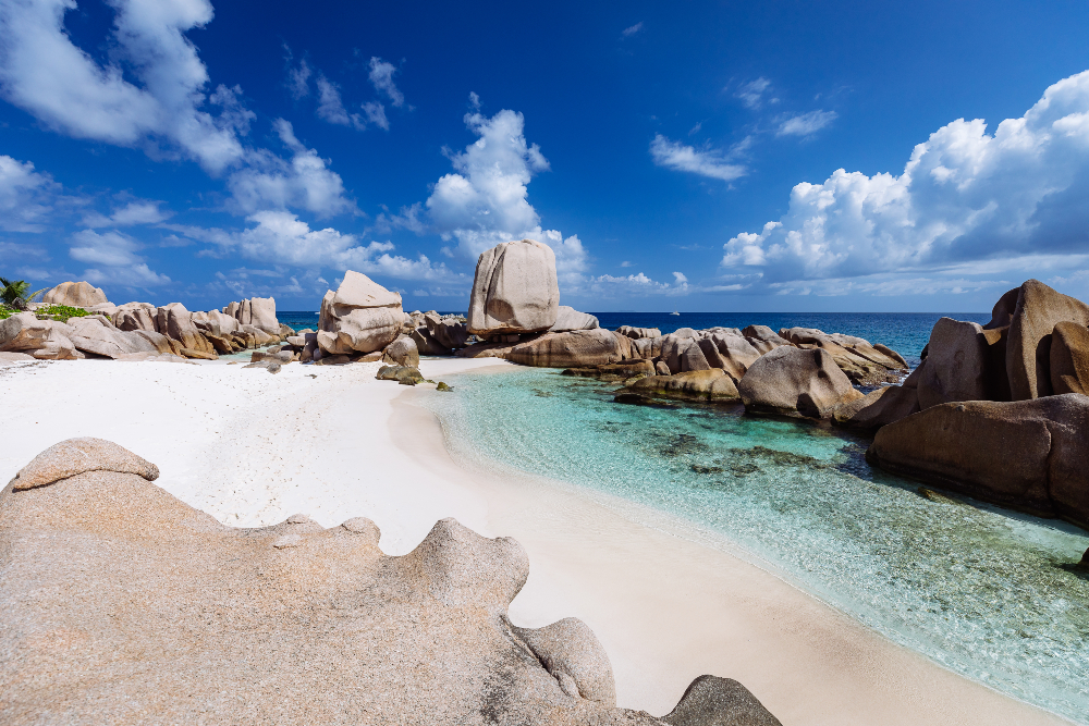Giant granite boulders surrounding white sandy beach and clear waters - Anse Morran 