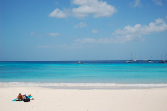 Man laying on blue towel on tropical beach