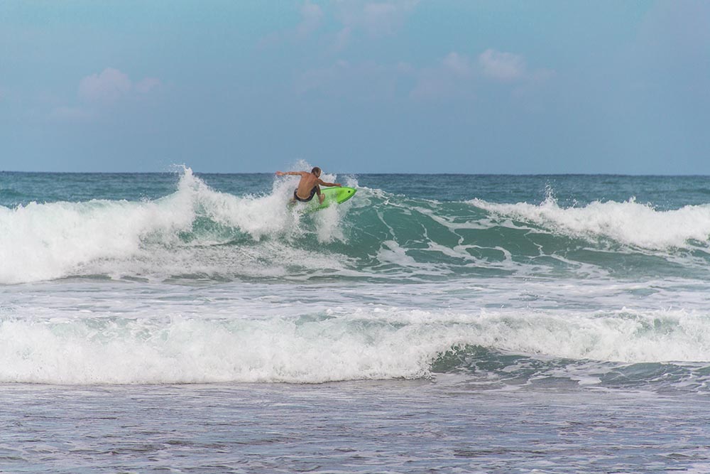 Man surfing big waves off a tropical beach