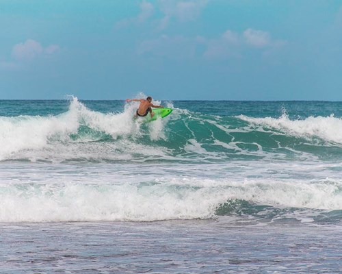 Man surfing big waves off a tropical beach