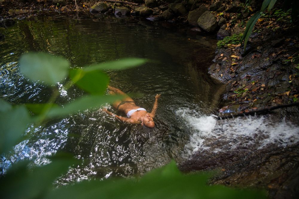 Woman relaxing in a natural pool in the middle of a rainforest