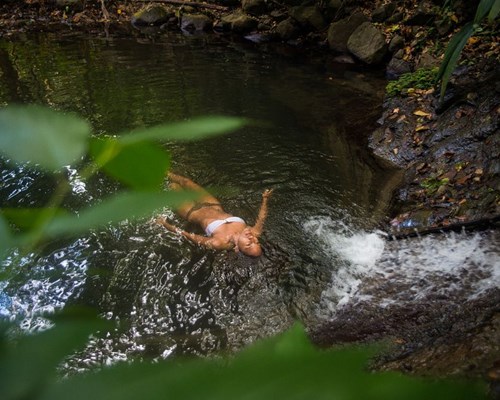 Woman relaxing in a natural pool in the middle of a rainforest