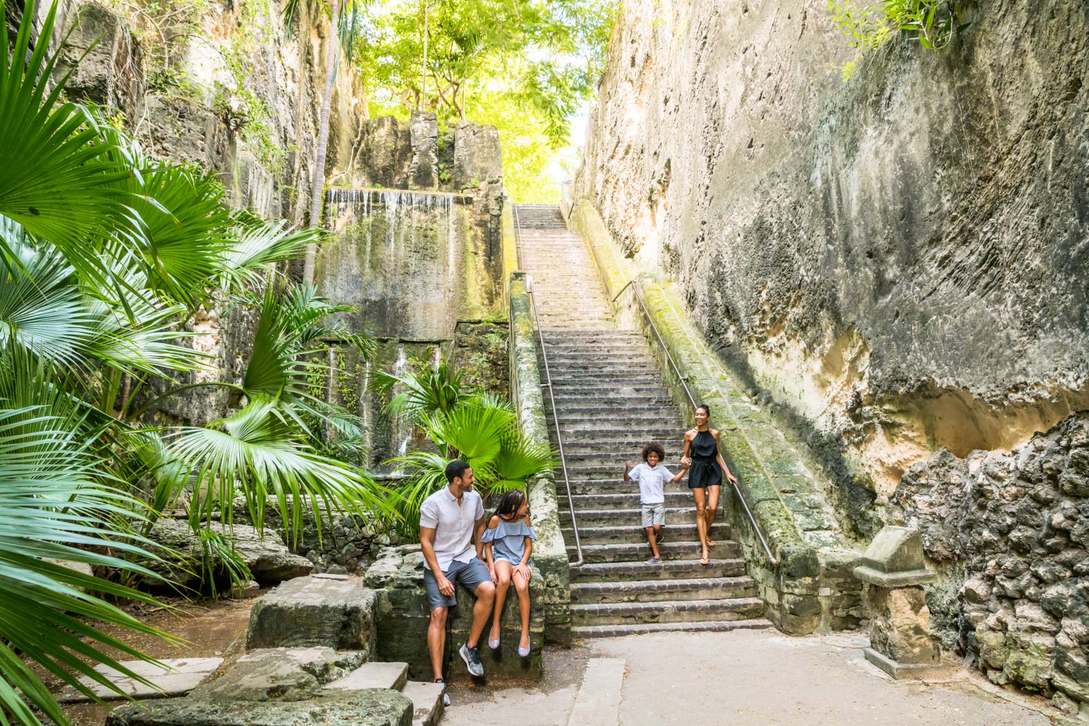 A family walking down a large stone staircase in the jungle