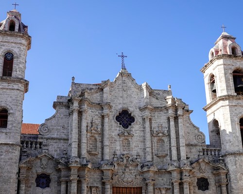 Looking up at a large catholic building with a background of blue sky