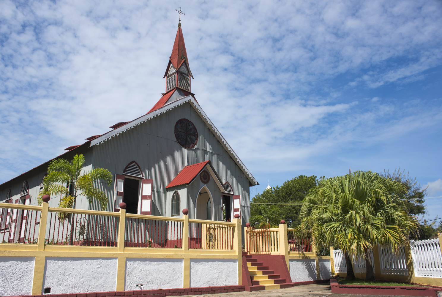 Exterior of a modern grey church with red roof and spire