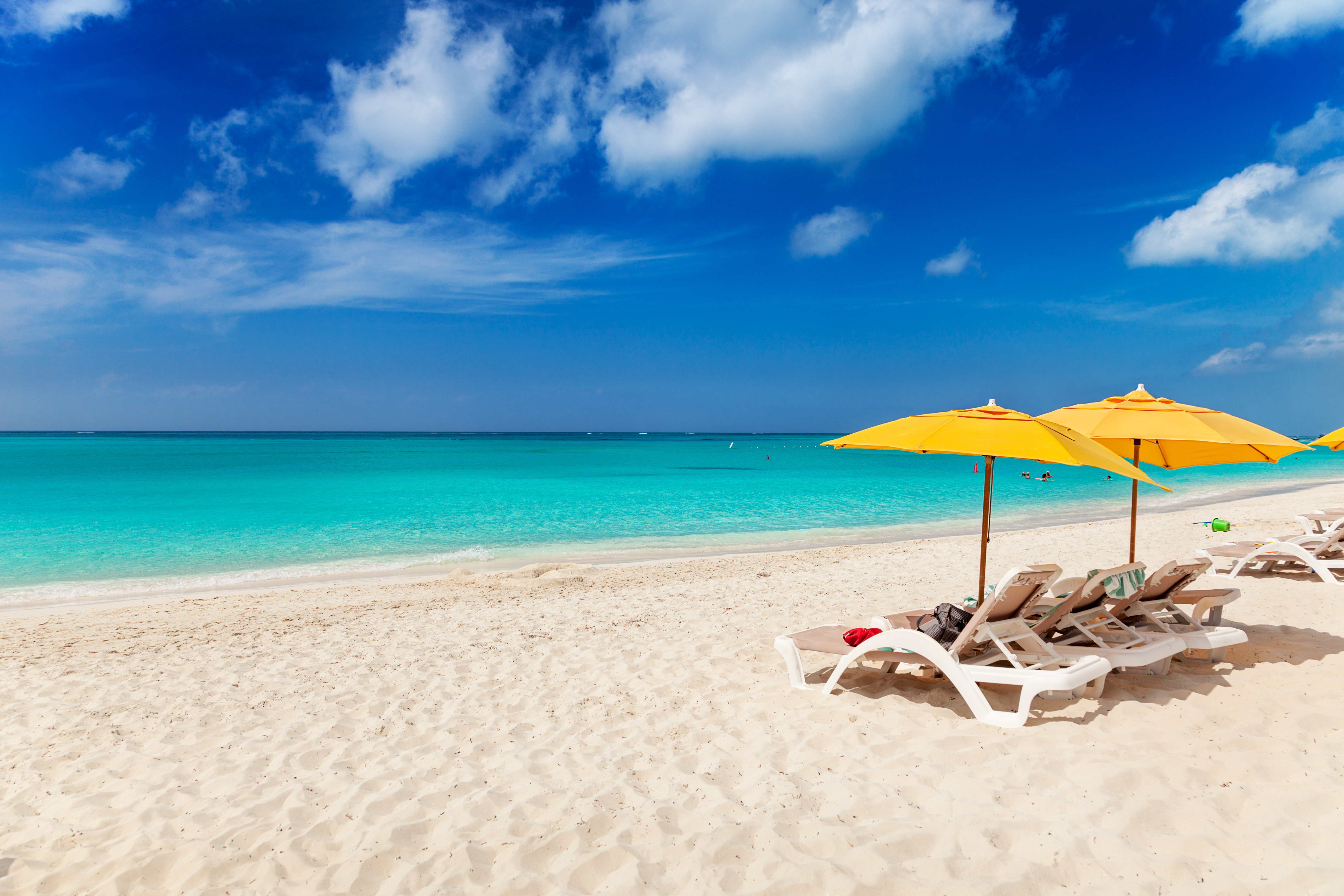 White deckchairs with yellow sun umbrellas on a pristine white beach