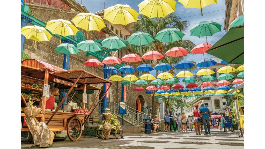 People walking on a market street underneath colourful umbrella's