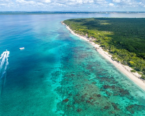 Speed boat driving past a tropical island with white sand beach