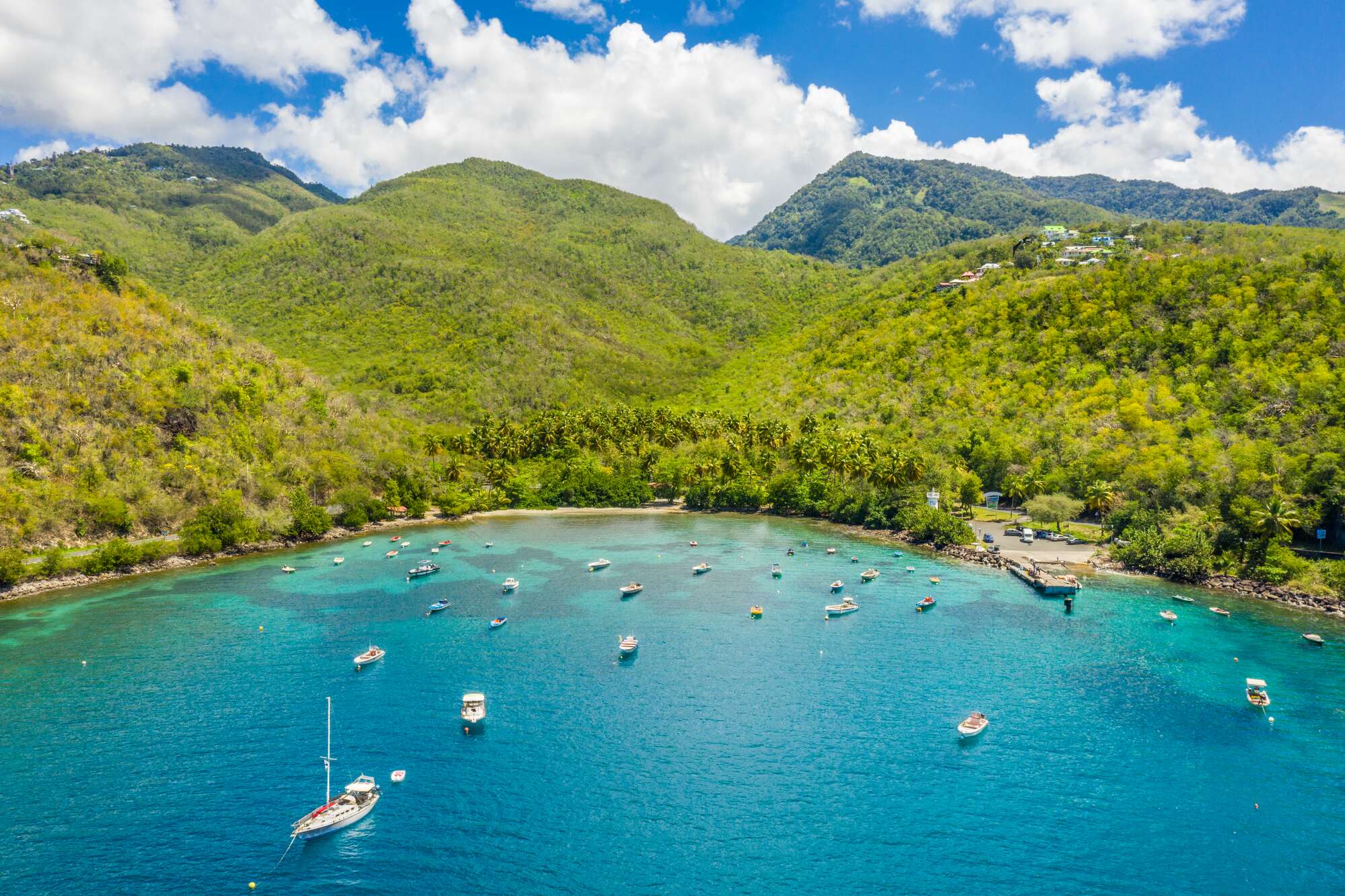 Aerial view of yachts docked up in tropical beach cove with bright blue waters
